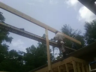 Carpenter setting a ridge beam over a new addition frame — Ice Dam Removal by Roofing Brothers in North Pitcher