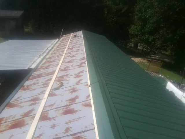 Old rusted panels beside newly installed green metal roofing — Wind Damage Roof Repair by Roofing Brothers in North Pitcher