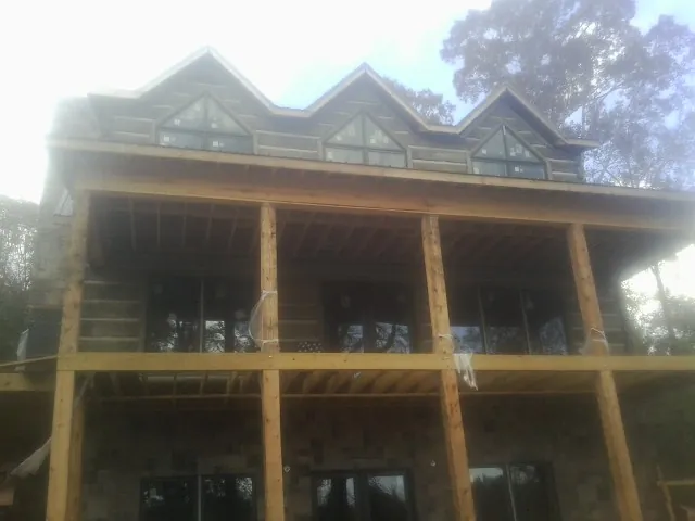 Dormers and porch framing on a large log home under construction — Roof Coating work by our crew in North Pitcher