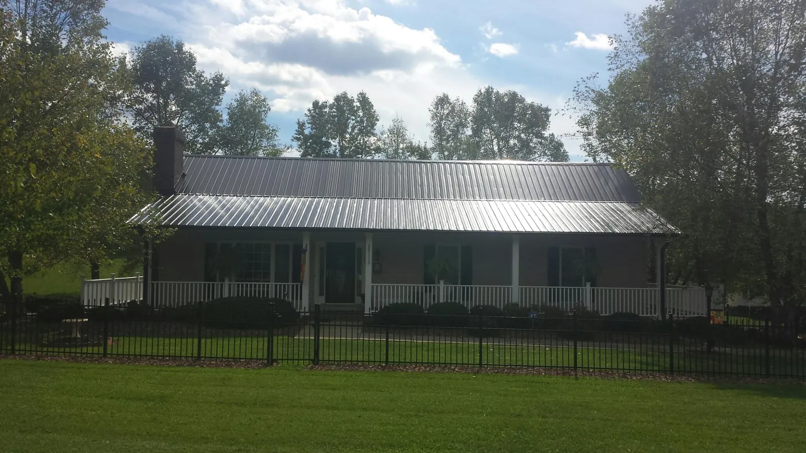 Gray metal roof on a brick ranch with a full width front porch — Gutter Guard Installation work by our crew in North Pitcher
