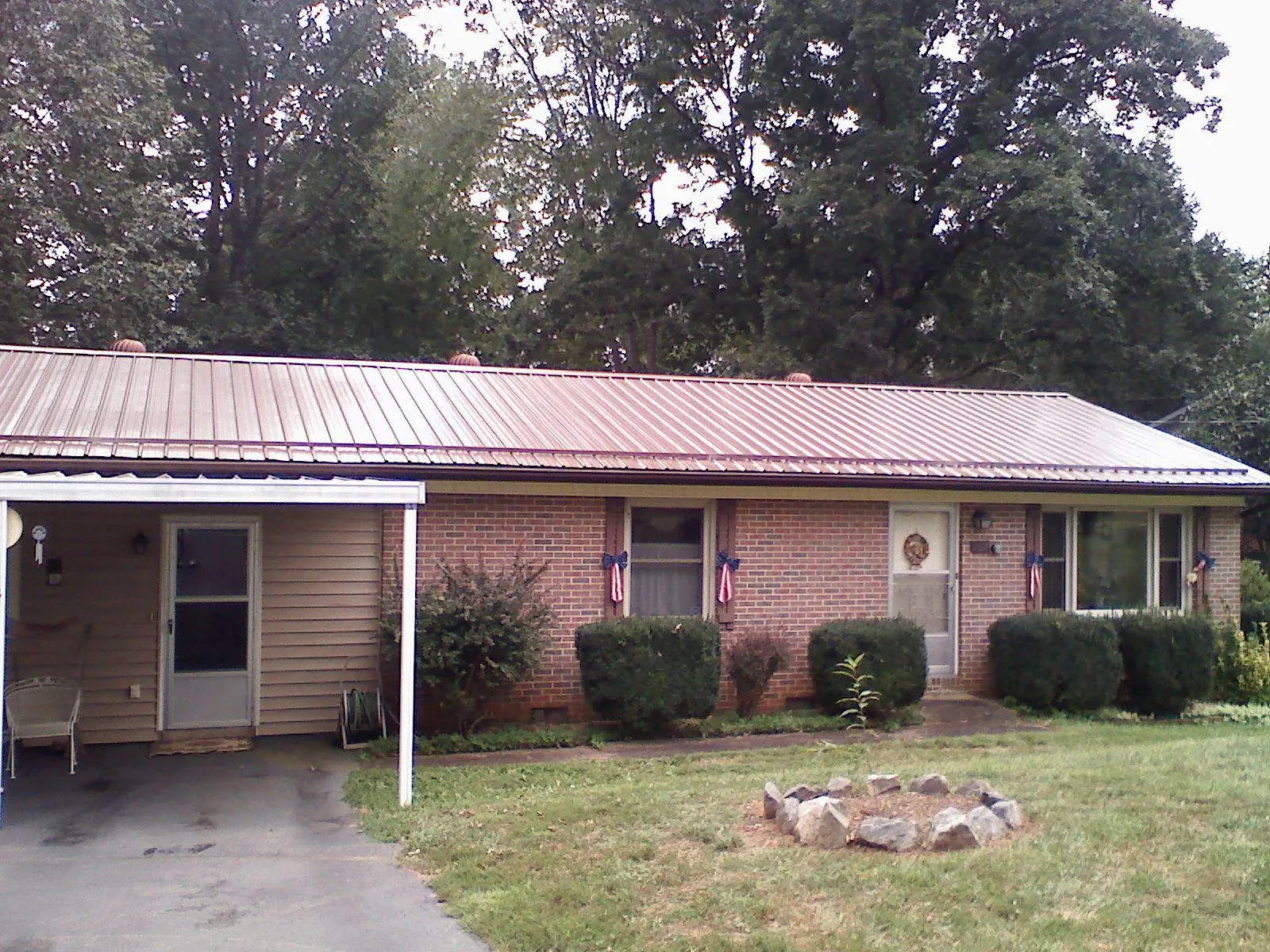 Bronze metal roof and carport on a brick ranch home — Roof Repair work by our crew in North Pitcher