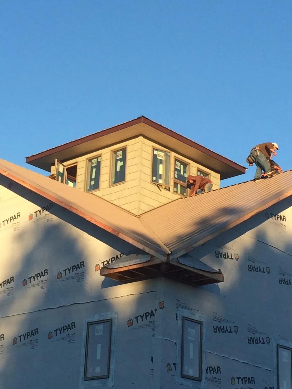 Roofers working around a rooftop cupola on a new metal roof at sunset — Roof Waterproofing in North Pitcher by Roofing Brothers